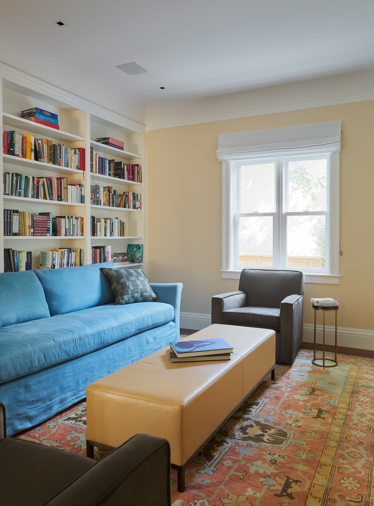 Foto di un soggiorno stile americano di medie dimensioni e chiuso con libreria, pareti gialle, parquet scuro, nessun camino, nessuna TV e pavimento marrone
