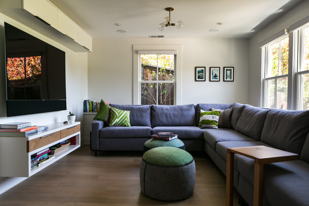 Ejemplo de sala de estar clásica renovada con paredes blancas, suelo de madera en tonos medios, televisor colgado en la pared y suelo marrón