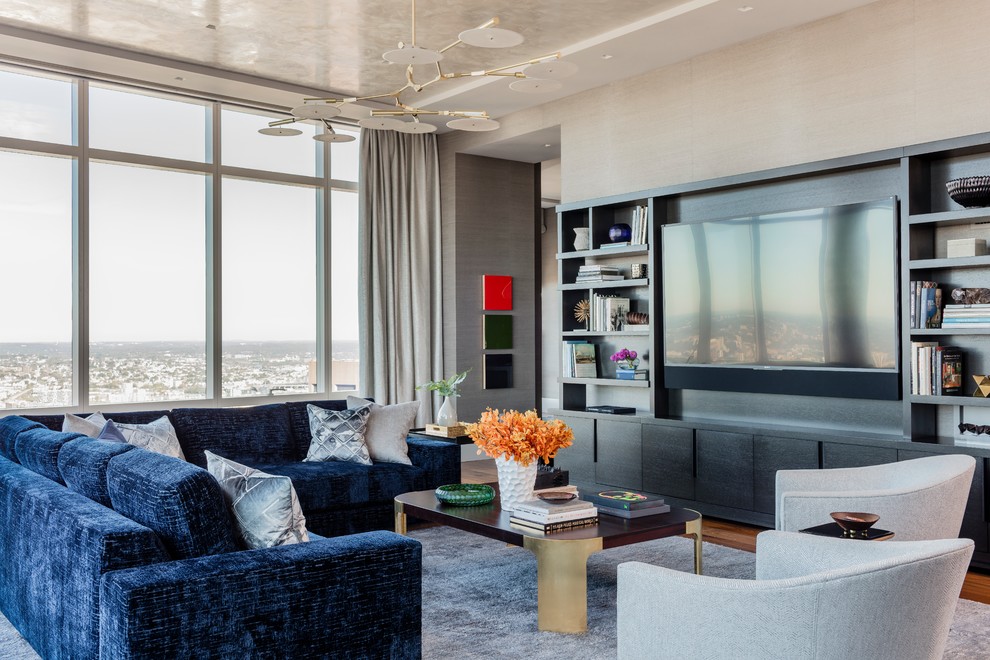 Foto de sala de estar abierta contemporánea grande con paredes grises, suelo de madera en tonos medios y pared multimedia
