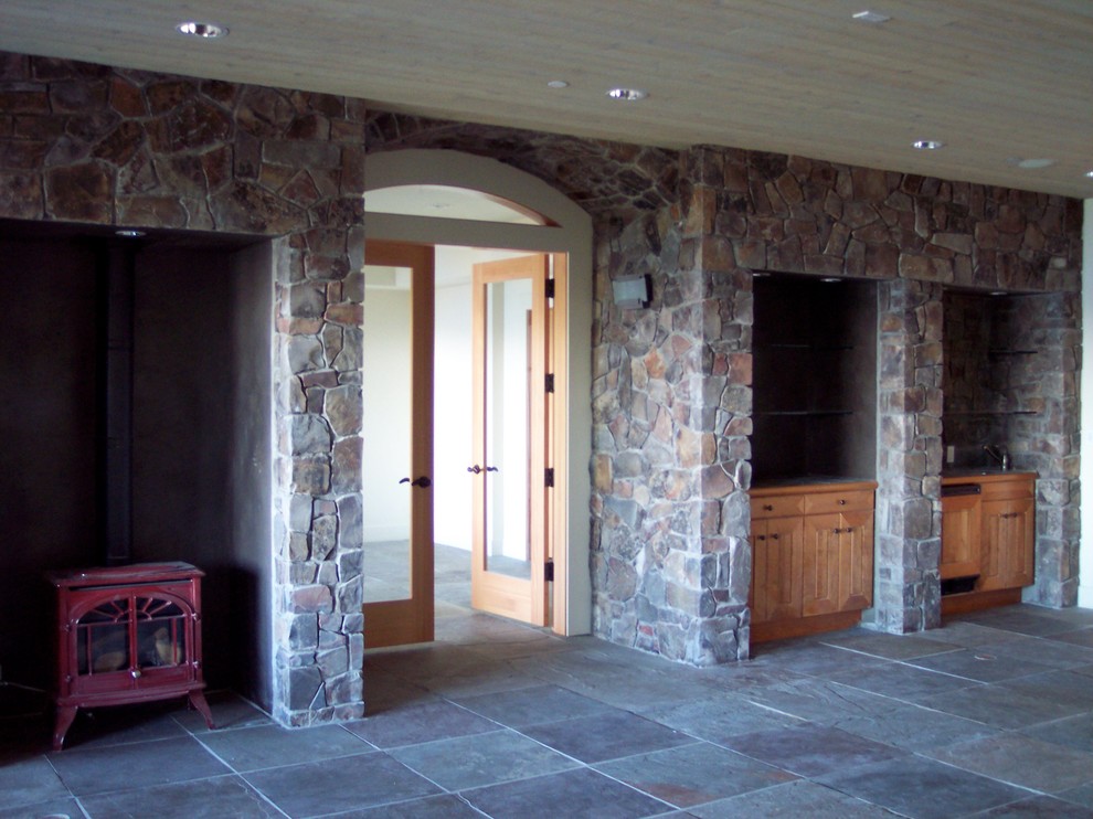 Idée de décoration pour une grande salle de séjour design ouverte avec salle de jeu, un sol en ardoise, une cheminée standard et un manteau de cheminée en pierre.