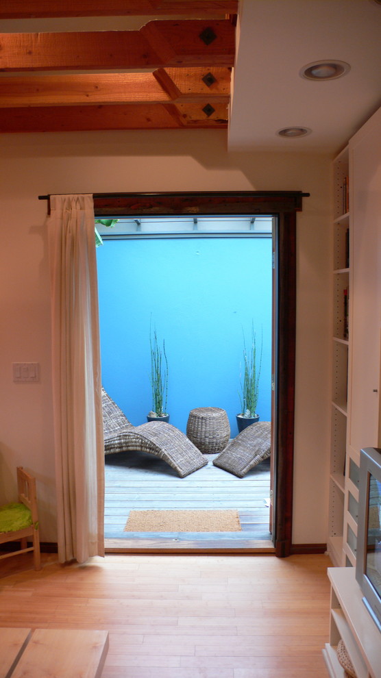 Diseño de sala de estar con biblioteca tipo loft marinera pequeña con paredes blancas, suelo de bambú y pared multimedia