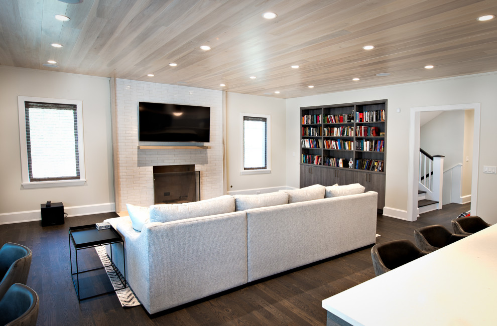 Foto di un soggiorno minimal aperto con libreria, pareti grigie, camino classico, cornice del camino piastrellata, TV a parete e soffitto in legno