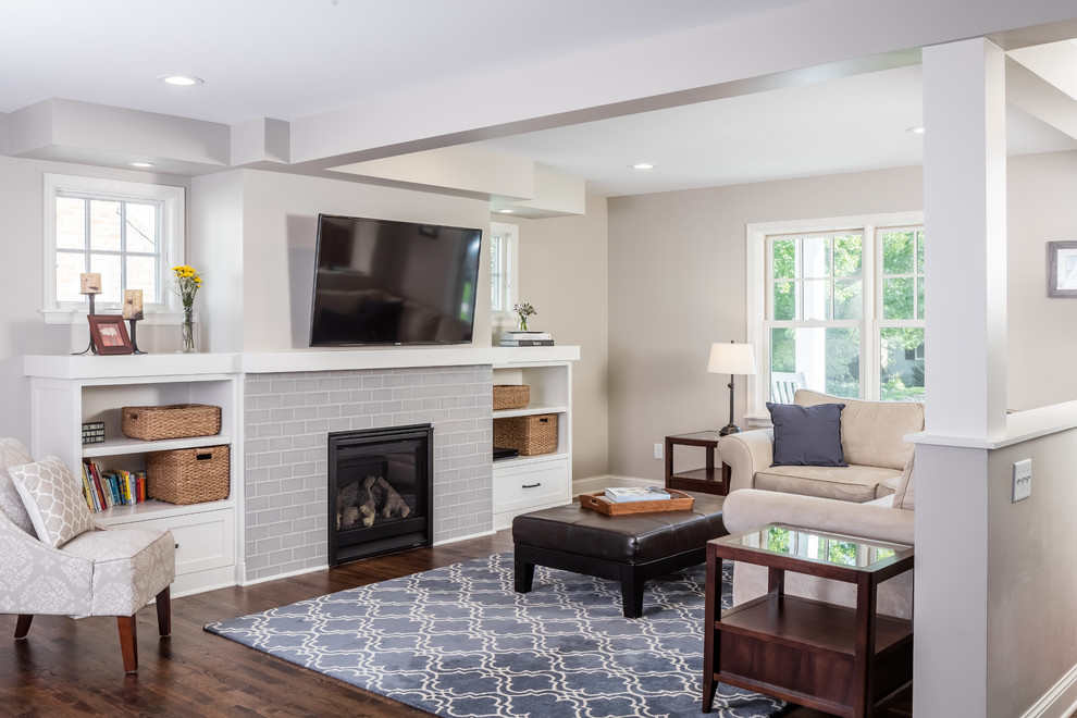 This is an example of a medium sized traditional open plan games room in Minneapolis with grey walls, dark hardwood flooring, a standard fireplace, a tiled fireplace surround and a wall mounted tv.