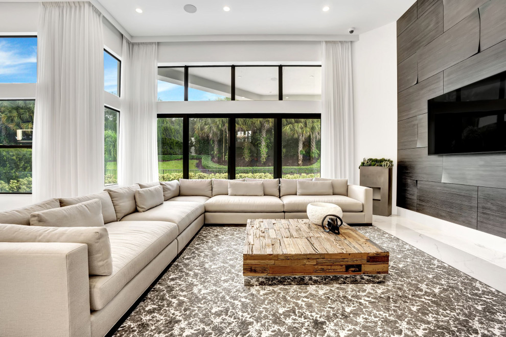 Imagen de sala de estar abierta actual grande con paredes blancas, suelo de baldosas de porcelana, televisor colgado en la pared, suelo blanco y panelado