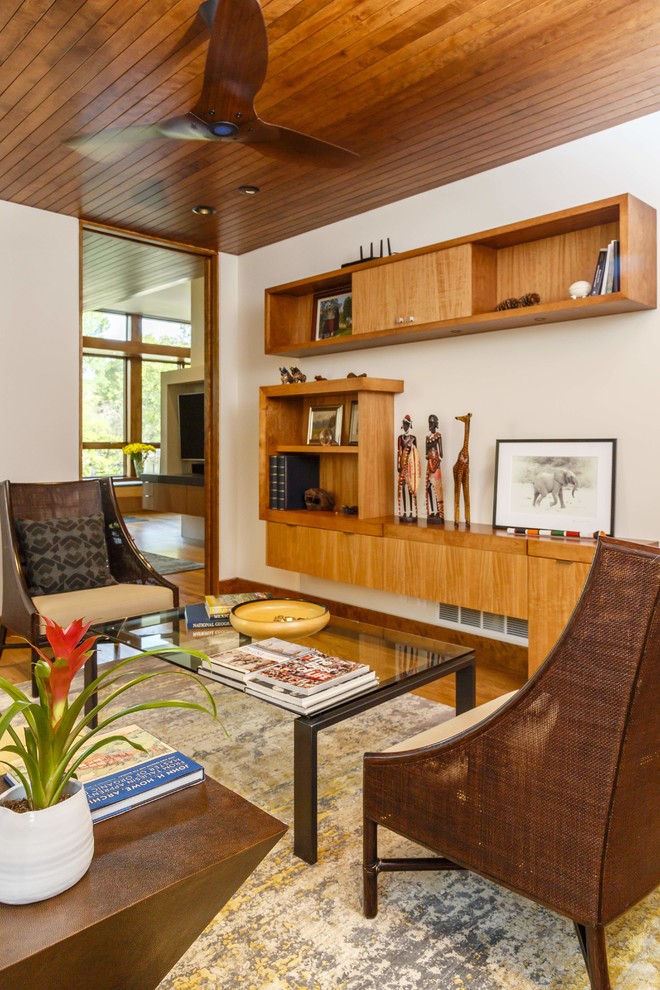 Foto de sala de estar con biblioteca cerrada minimalista pequeña sin chimenea y televisor con paredes blancas y suelo de madera en tonos medios