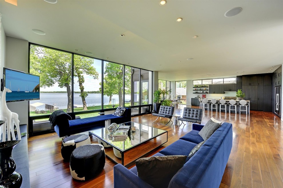 Immagine di un soggiorno contemporaneo aperto con pavimento in legno massello medio, porta TV ad angolo e pavimento marrone