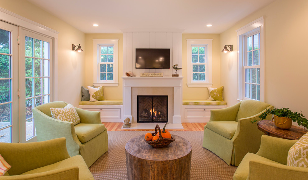 Mid-sized beach style enclosed light wood floor family room photo in Boston with yellow walls, a standard fireplace, a plaster fireplace and a wall-mounted tv