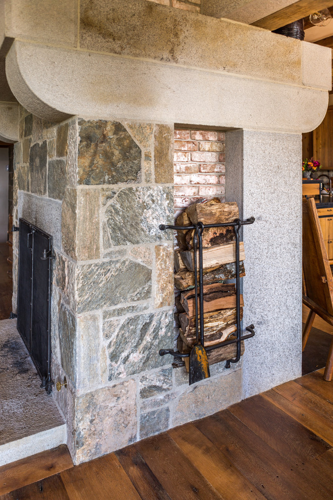 Cette photo montre une grande salle de séjour montagne fermée avec un sol en bois brun, une cheminée standard, un manteau de cheminée en brique et aucun téléviseur.