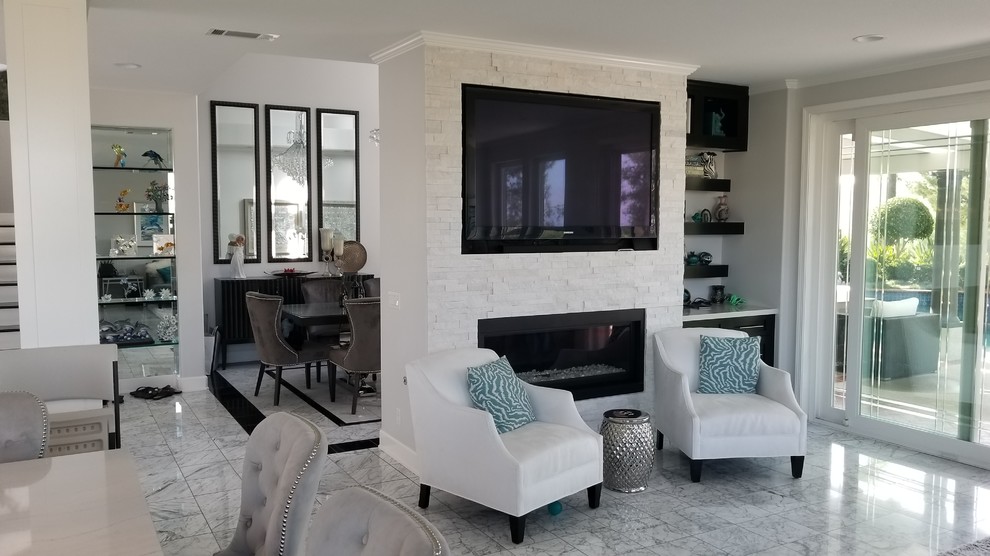 Photo of a medium sized classic open plan games room in Orange County with grey walls, marble flooring, a standard fireplace, a stone fireplace surround, a wall mounted tv and grey floors.