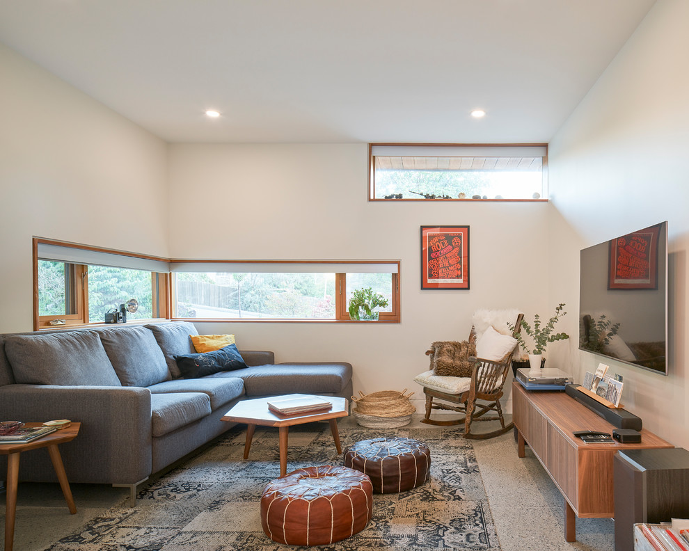 Idee per un soggiorno minimalista di medie dimensioni con pareti bianche, pavimento in cemento, pavimento grigio e TV a parete