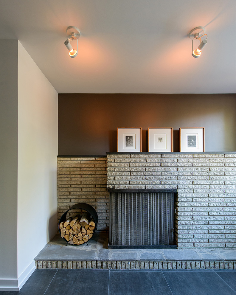 Стильный дизайн: гостиная комната в стиле ретро с белыми стенами, полом из керамогранита, угловым камином и фасадом камина из кирпича - последний тренд