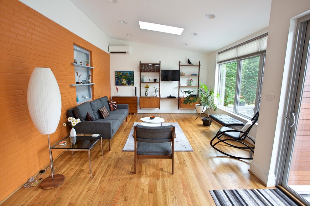 Idee per un soggiorno minimalista di medie dimensioni e aperto con pareti arancioni e pavimento in legno massello medio