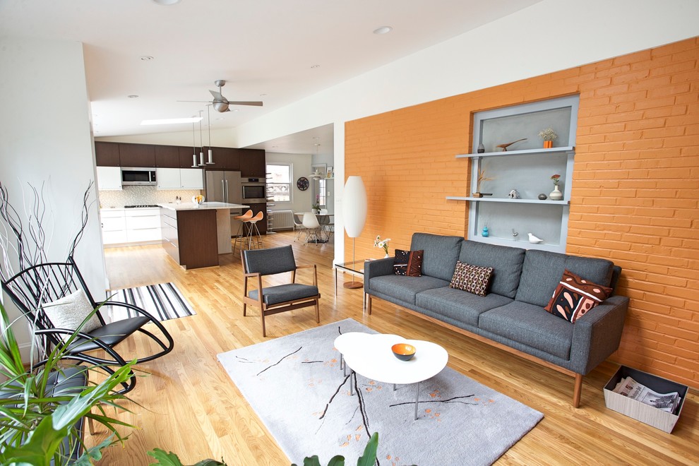This is an example of a medium sized modern open plan games room in DC Metro with orange walls and medium hardwood flooring.