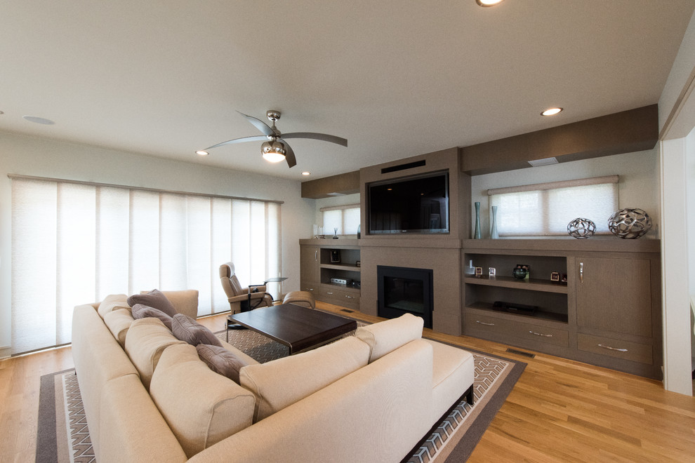 Imagen de sala de estar abierta contemporánea grande con paredes blancas, suelo de madera clara y pared multimedia