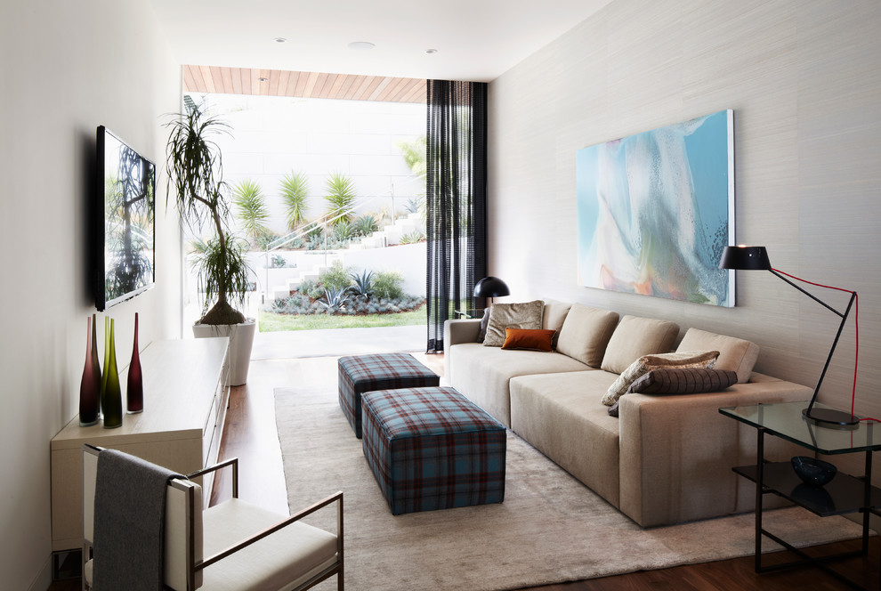 Modelo de sala de estar abierta moderna de tamaño medio con paredes grises, suelo de madera clara y televisor colgado en la pared