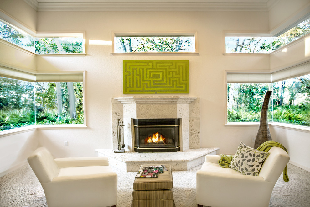 Modelo de sala de estar actual con paredes beige, moqueta, todas las chimeneas, marco de chimenea de piedra y suelo beige