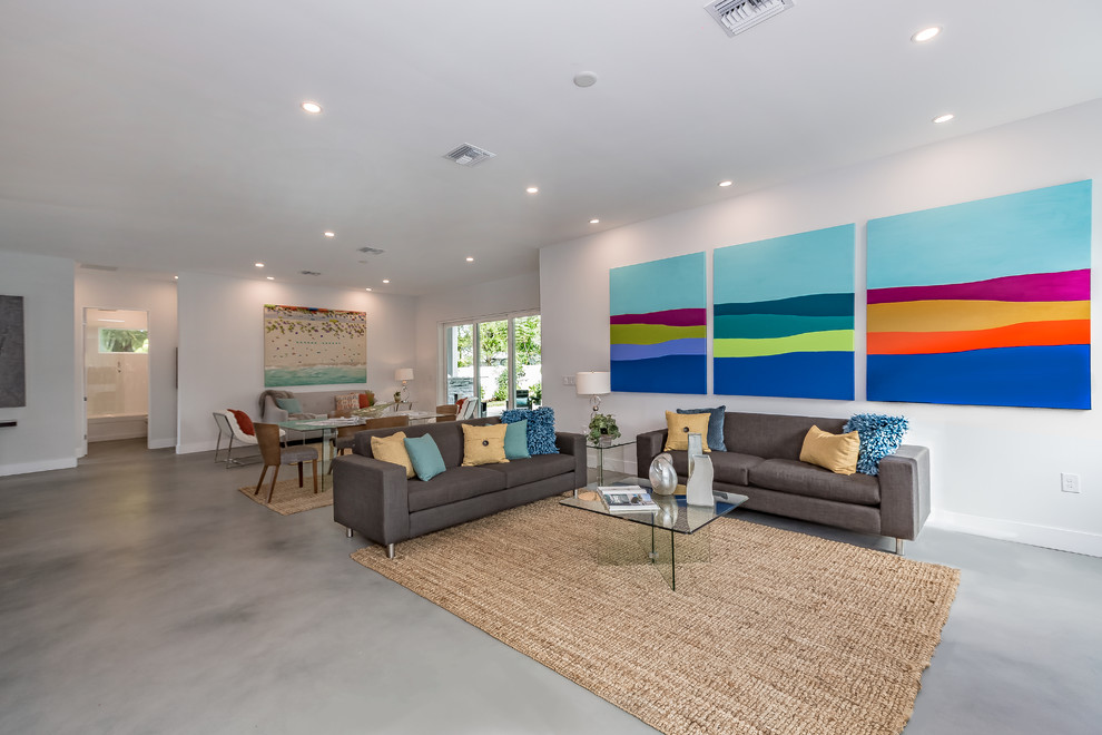 Immagine di un grande soggiorno minimalista aperto con pareti bianche, pavimento in cemento e pavimento grigio