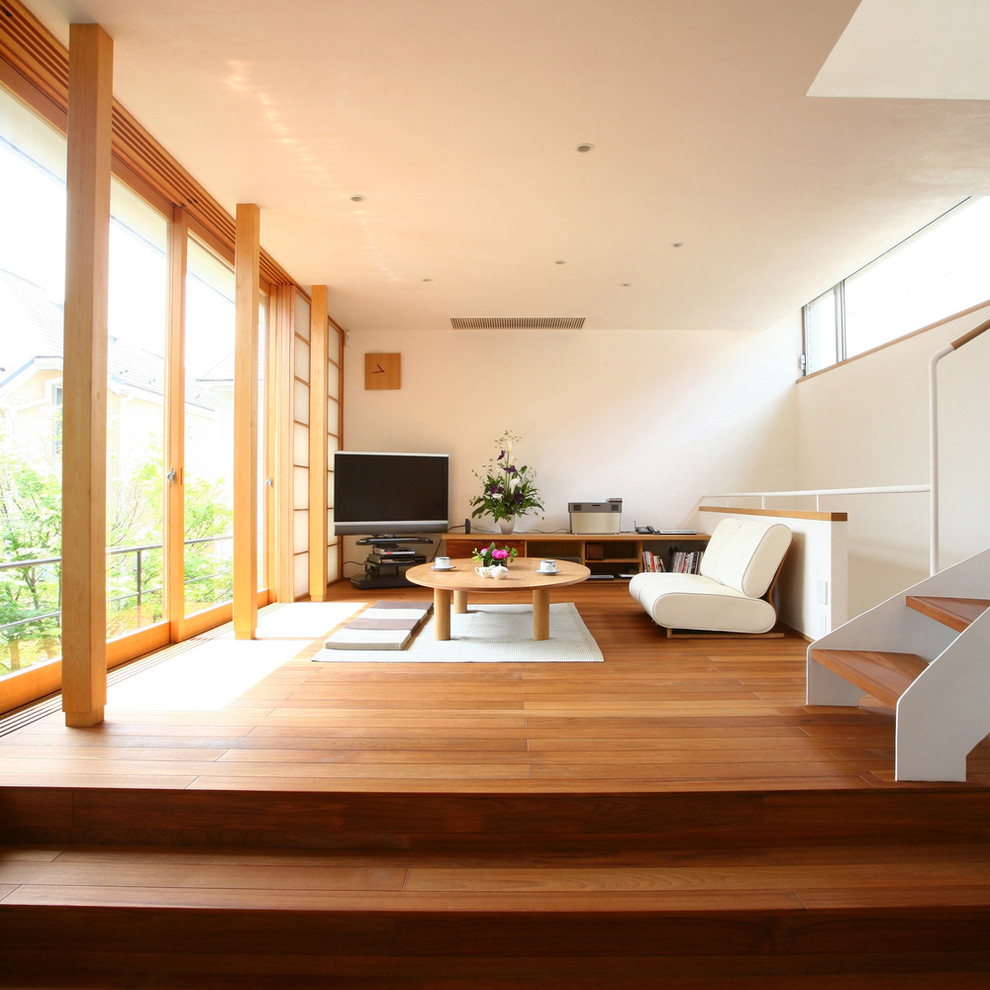 Immagine di un soggiorno etnico con pareti bianche, pavimento in legno massello medio e porta TV ad angolo