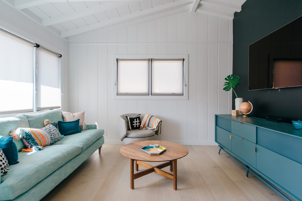 Kleines, Abgetrenntes Wohnzimmer mit schwarzer Wandfarbe, hellem Holzboden, TV-Wand, beigem Boden und Holzdielenwänden in Orange County