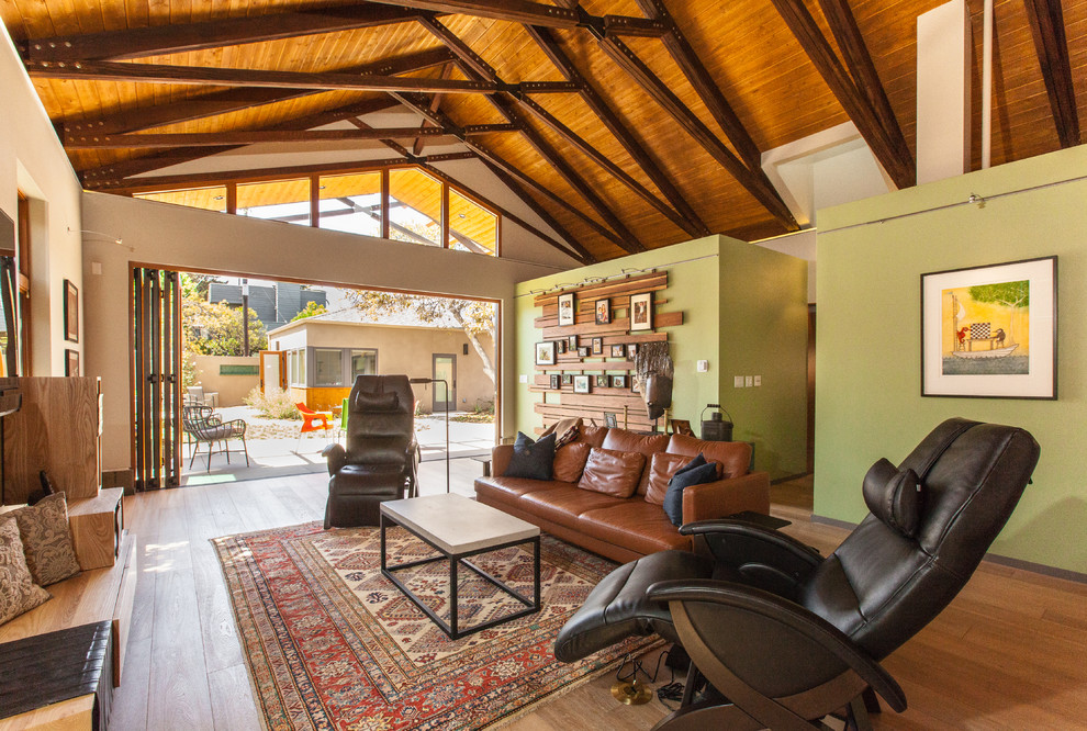 Offenes Mid-Century Wohnzimmer mit grüner Wandfarbe und braunem Holzboden in San Diego