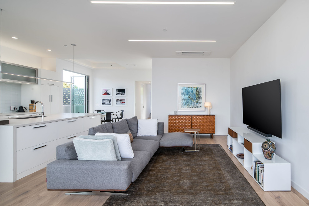 サンディエゴにある高級な中くらいなコンテンポラリースタイルのおしゃれなオープンリビング (グレーの壁、淡色無垢フローリング、暖炉なし、壁掛け型テレビ、茶色い床) の写真