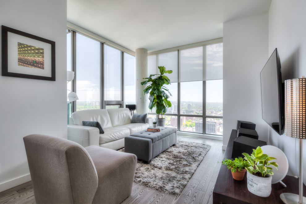 Idee per un piccolo soggiorno minimalista aperto con pareti bianche, pavimento in legno massello medio, TV a parete e pavimento grigio