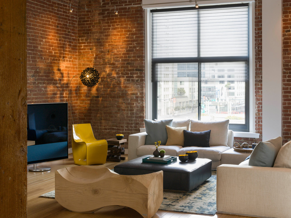 Imagen de sala de estar tipo loft contemporánea grande con televisor independiente, paredes blancas, suelo marrón, ladrillo y suelo de madera clara