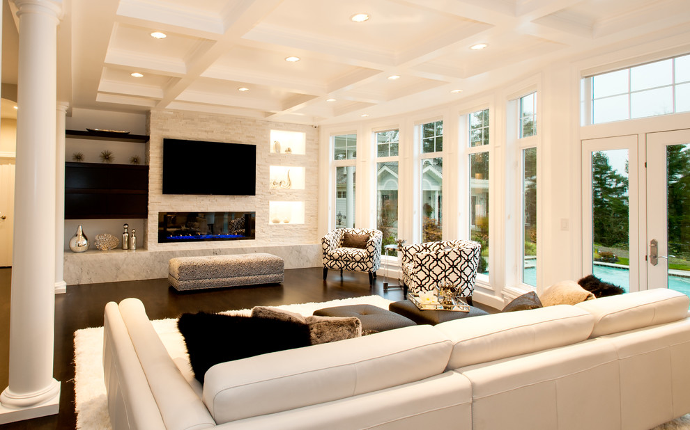 Diseño de sala de estar abierta minimalista grande con paredes grises, suelo de madera en tonos medios, todas las chimeneas, marco de chimenea de piedra y pared multimedia