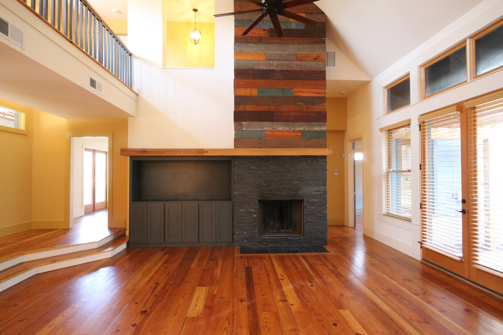 Ejemplo de sala de estar abierta actual de tamaño medio con paredes beige, suelo de madera en tonos medios y marco de chimenea de piedra