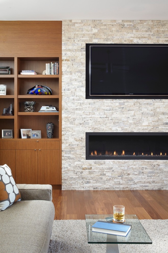 Aménagement d'une grande salle de séjour moderne ouverte avec un sol en bois brun, une cheminée standard, un manteau de cheminée en pierre et un téléviseur encastré.