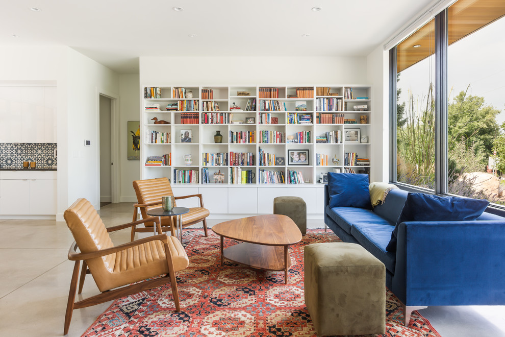 Diseño de sala de estar con biblioteca abierta retro sin chimenea con paredes blancas, suelo beige, alfombra y pared multimedia