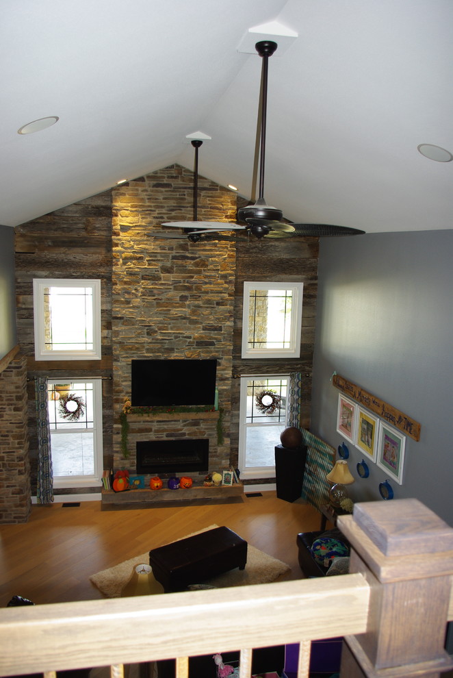 Example of a mid-sized country enclosed light wood floor family room design in St Louis with blue walls, a standard fireplace, a stone fireplace and a wall-mounted tv