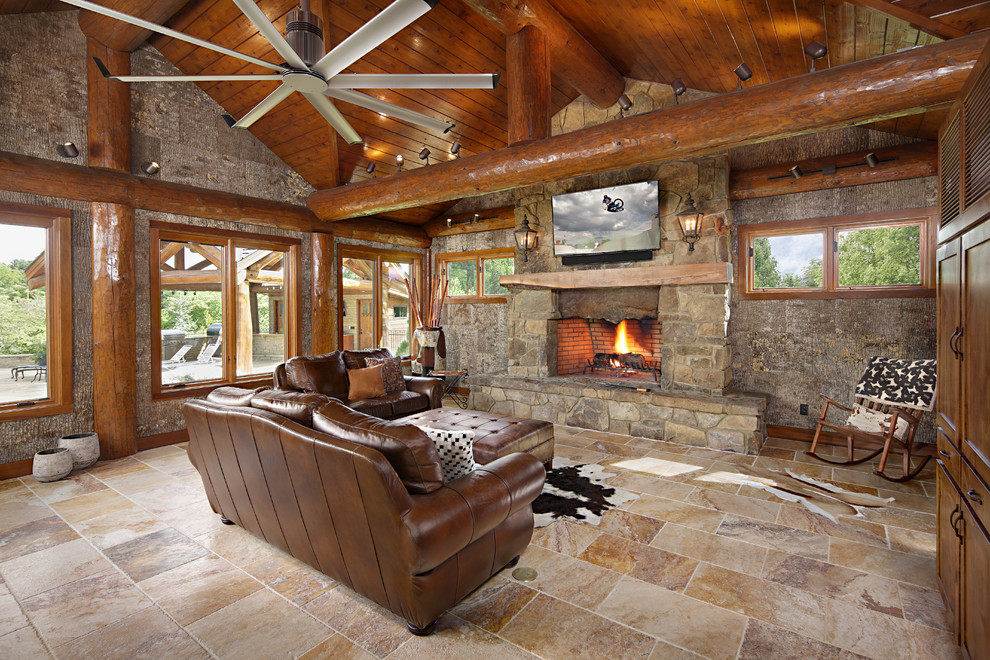 На фото: гостиная комната в стиле рустика с стандартным камином, фасадом камина из камня и телевизором на стене с
