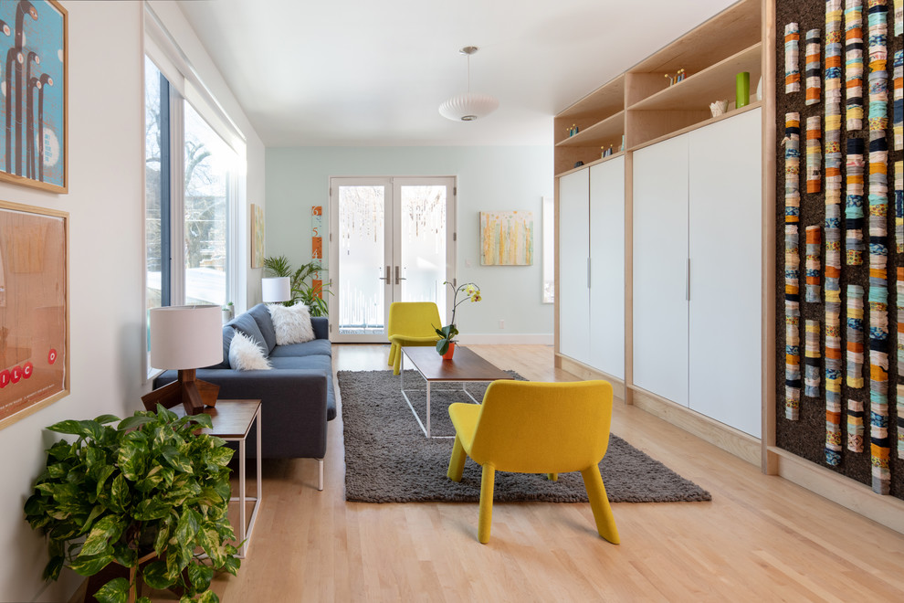 Diseño de sala de estar cerrada nórdica de tamaño medio sin chimenea con paredes azules, suelo de madera clara, televisor retractable, suelo beige y alfombra