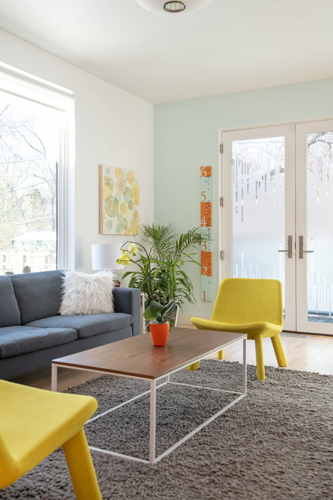 На фото: изолированная гостиная комната среднего размера в скандинавском стиле с синими стенами, светлым паркетным полом, скрытым телевизором и бежевым полом без камина с
