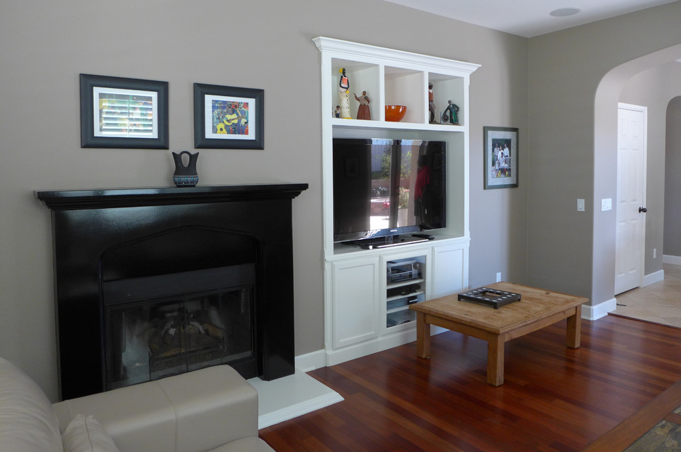 Imagen de sala de estar abierta minimalista de tamaño medio con paredes grises, suelo de madera en tonos medios, todas las chimeneas, marco de chimenea de madera y pared multimedia