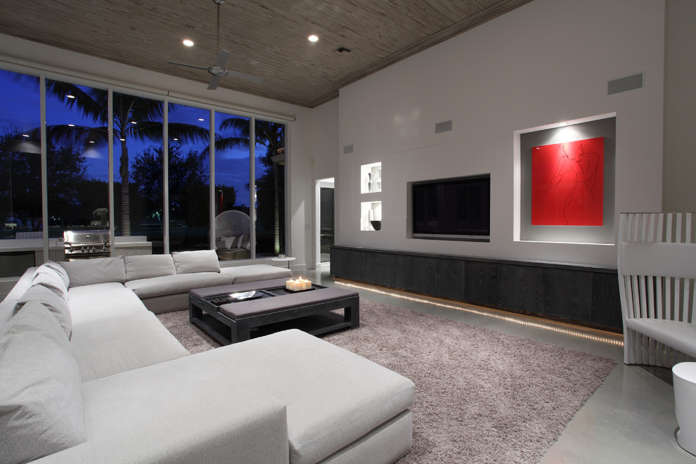 Esempio di un grande soggiorno minimalista con pareti bianche, pavimento in cemento, nessun camino e parete attrezzata