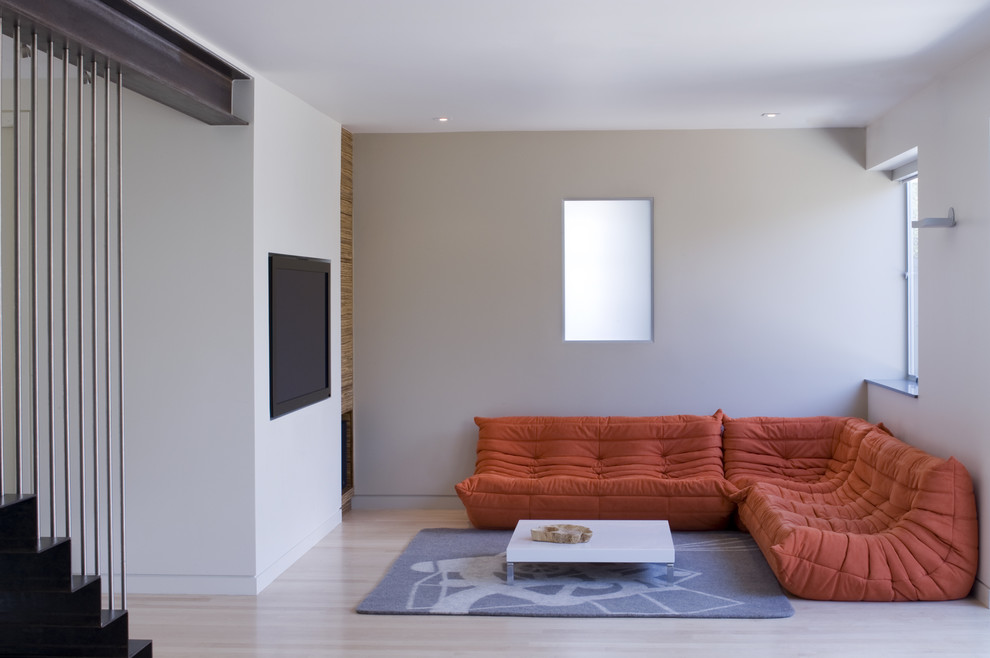 Idéer för ett modernt allrum, med beige väggar, ljust trägolv och en väggmonterad TV