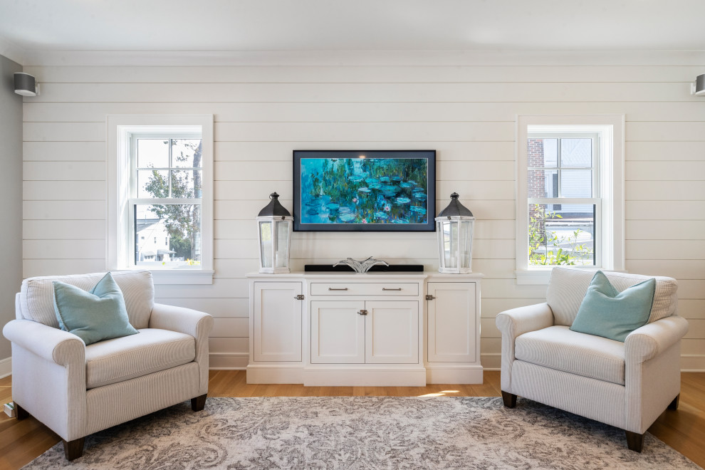 Diseño de sala de estar abierta campestre grande sin chimenea con paredes blancas, suelo de madera clara, televisor colgado en la pared y suelo marrón