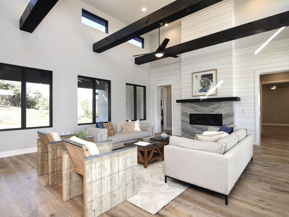 Inspiration for a large rural open plan games room in Austin with medium hardwood flooring, a standard fireplace, a wall mounted tv and brown floors.