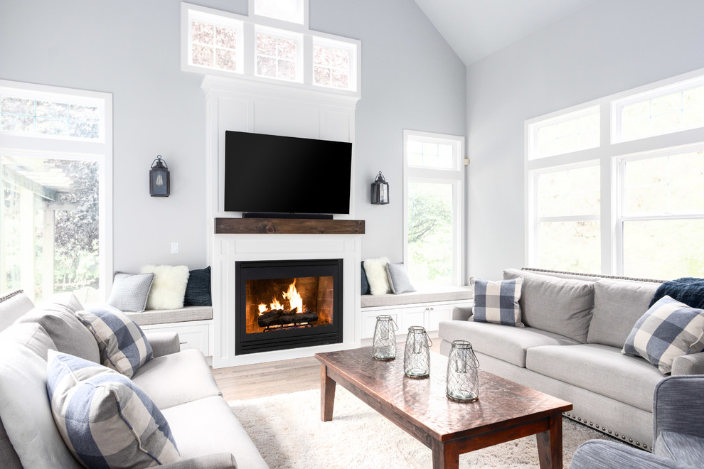 Imagen de sala de estar de estilo de casa de campo con paredes grises, suelo de madera en tonos medios, todas las chimeneas y suelo marrón