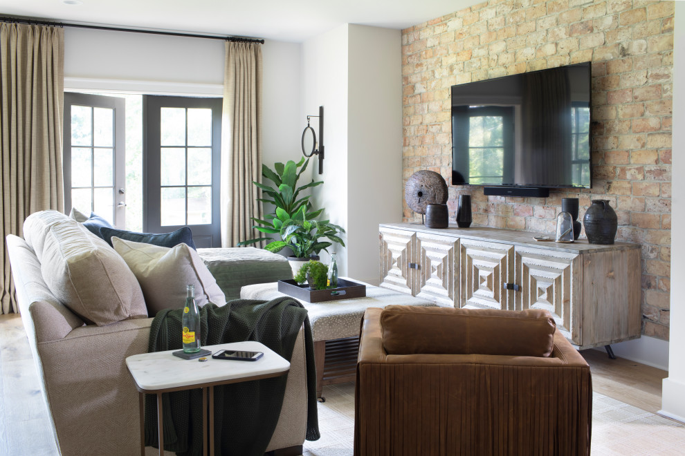 Imagen de sala de estar abierta campestre grande sin chimenea con paredes blancas, suelo de madera clara, televisor colgado en la pared y suelo beige