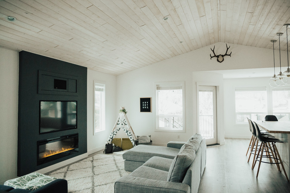 Diseño de salón abierto escandinavo de tamaño medio con paredes blancas, televisor colgado en la pared, chimenea lineal y suelo vinílico