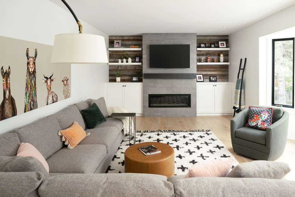 На фото: открытая гостиная комната в стиле неоклассика (современная классика) с белыми стенами, светлым паркетным полом, фасадом камина из плитки, телевизором на стене, горизонтальным камином и коричневым полом с