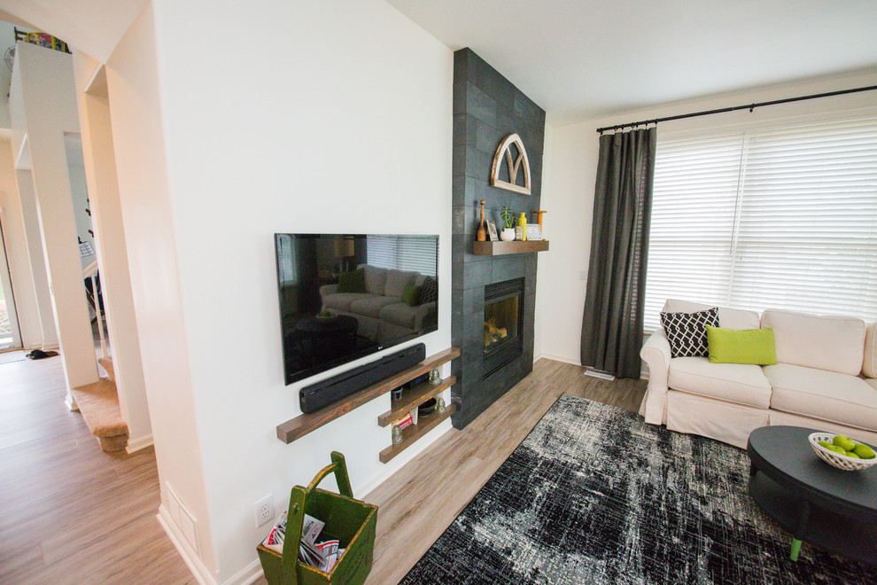 Cette photo montre une salle de séjour tendance de taille moyenne et ouverte avec un mur blanc, un sol en bois brun, une cheminée standard, un manteau de cheminée en pierre, un téléviseur fixé au mur et un sol marron.