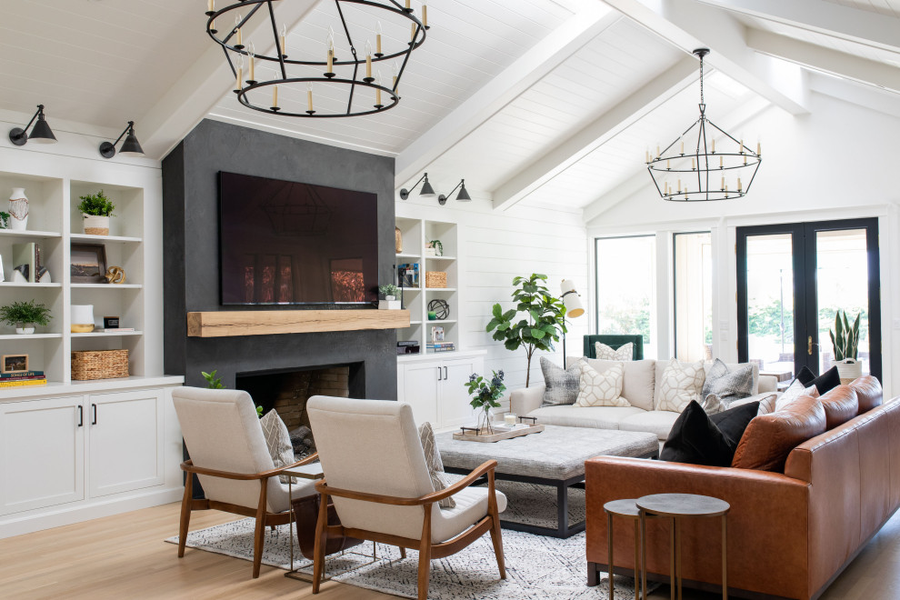 Modelo de sala de estar con barra de bar abierta campestre grande con paredes blancas, suelo de madera clara, todas las chimeneas y televisor colgado en la pared
