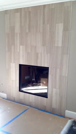 Réalisation d'une salle de séjour minimaliste de taille moyenne avec un mur gris, un sol en bois brun, une cheminée standard et un manteau de cheminée en pierre.
