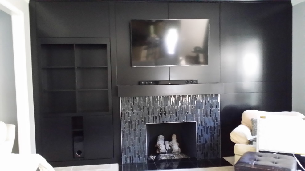 Идея дизайна: большая изолированная гостиная комната в стиле модернизм с черными стенами, полом из керамической плитки, стандартным камином, фасадом камина из плитки и телевизором на стене