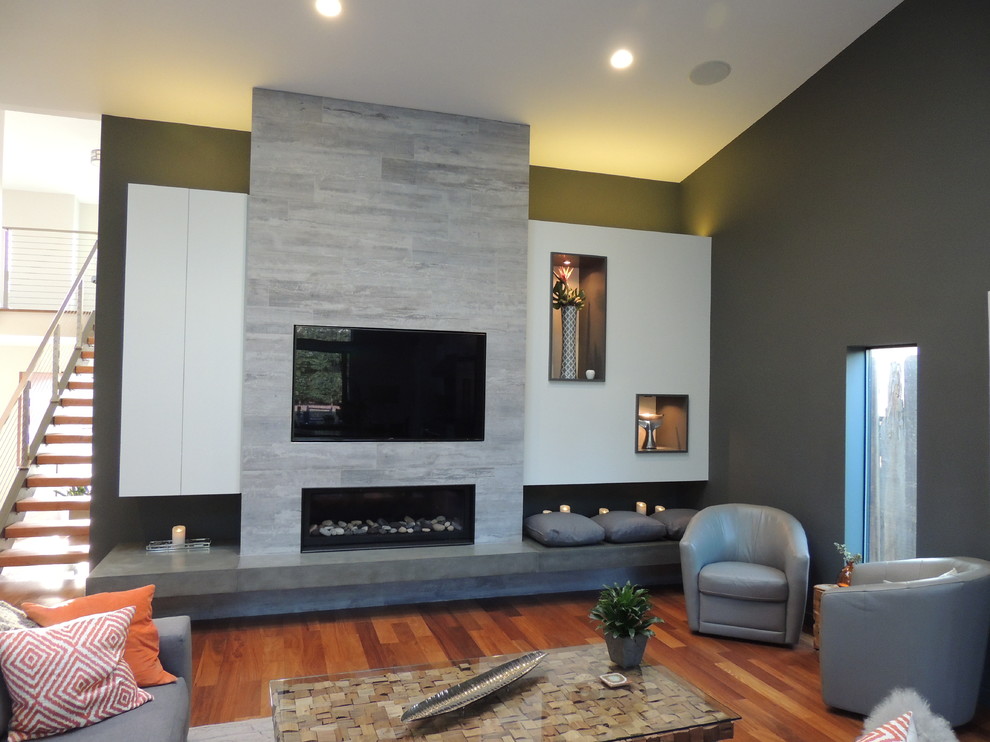 Foto de sala de estar tipo loft moderna con paredes grises, suelo de madera en tonos medios, chimenea lineal, marco de chimenea de baldosas y/o azulejos y pared multimedia
