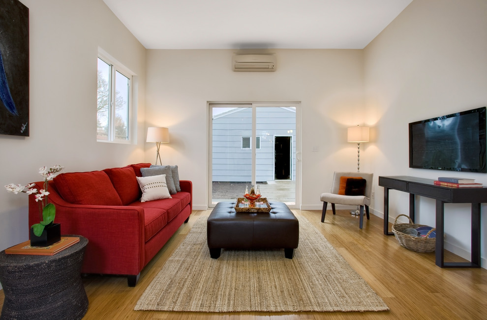 Ejemplo de sala de estar contemporánea con paredes beige, suelo de madera en tonos medios, televisor colgado en la pared y alfombra